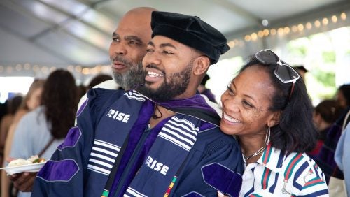 A graduate smiles and poses with loved ones.